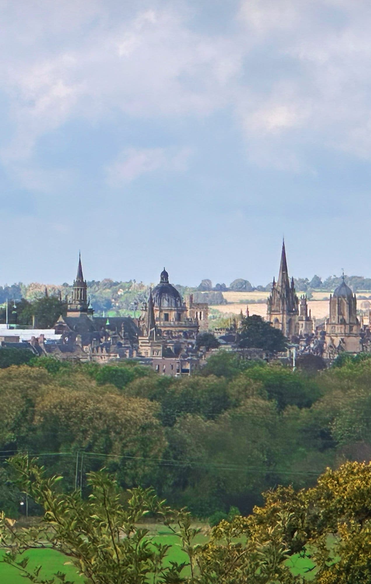 The spires of Oxford seen across green trees